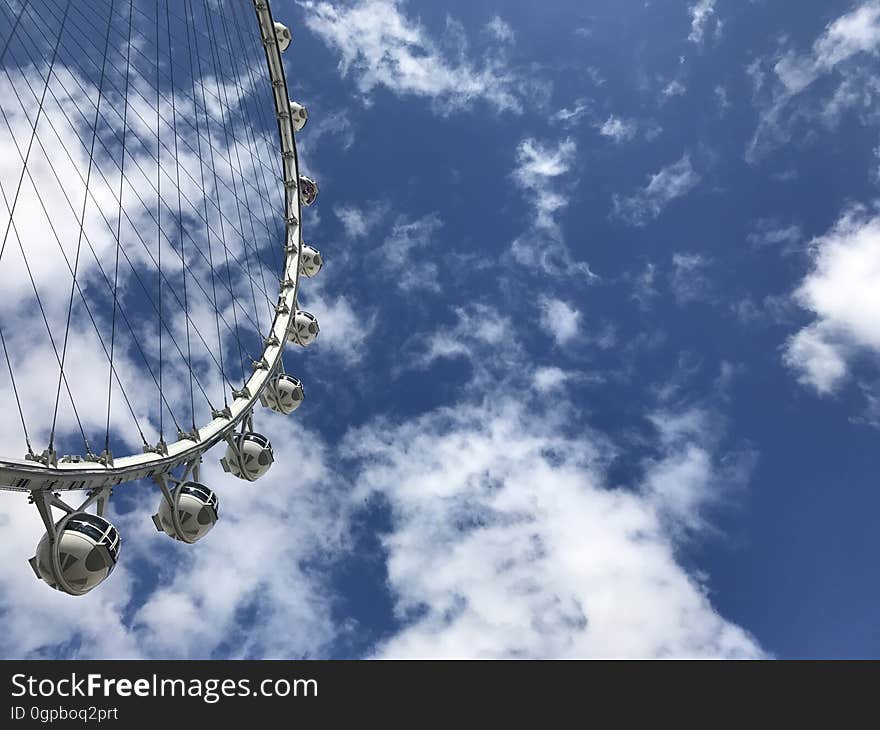 A white ferris wheel going around on a sunny day.