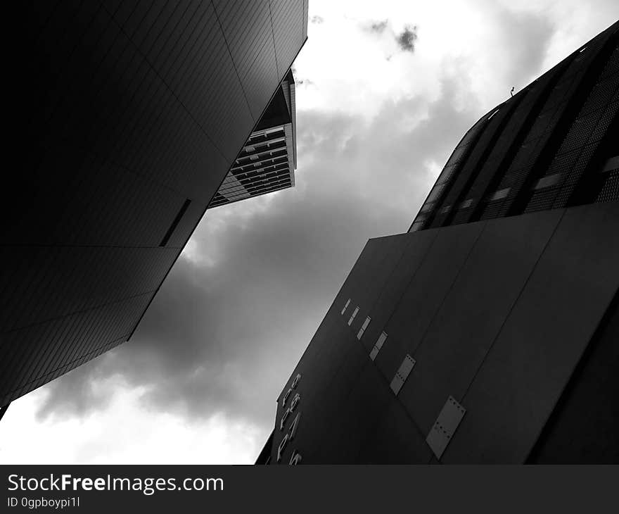 Architecture from an acute angle showing two high rise buildings (or skyscrapers) in low light, outlining some windows in the sides and producing an abstract background.