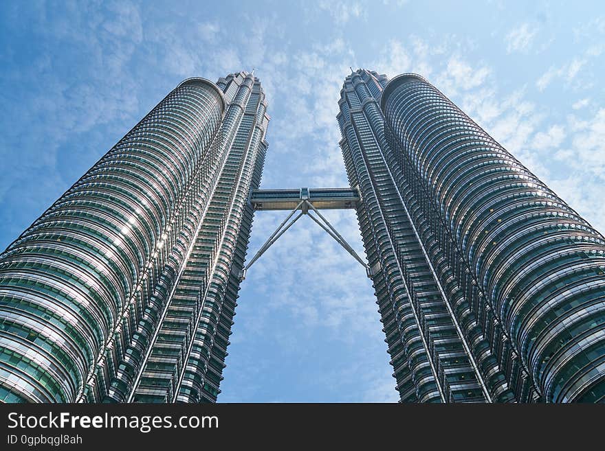 Petronas skyscraper with walking bridge between dual high rise towers against blue skies in Kuala Lumpur, Malaysia. Petronas skyscraper with walking bridge between dual high rise towers against blue skies in Kuala Lumpur, Malaysia.