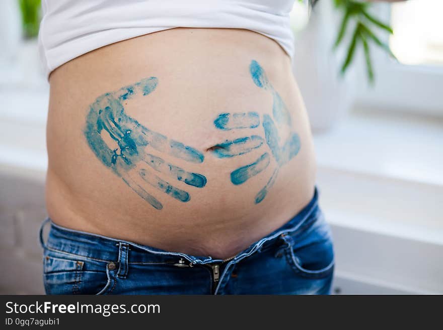 Close-up of a belly of a pregnant woman with prints of her palms