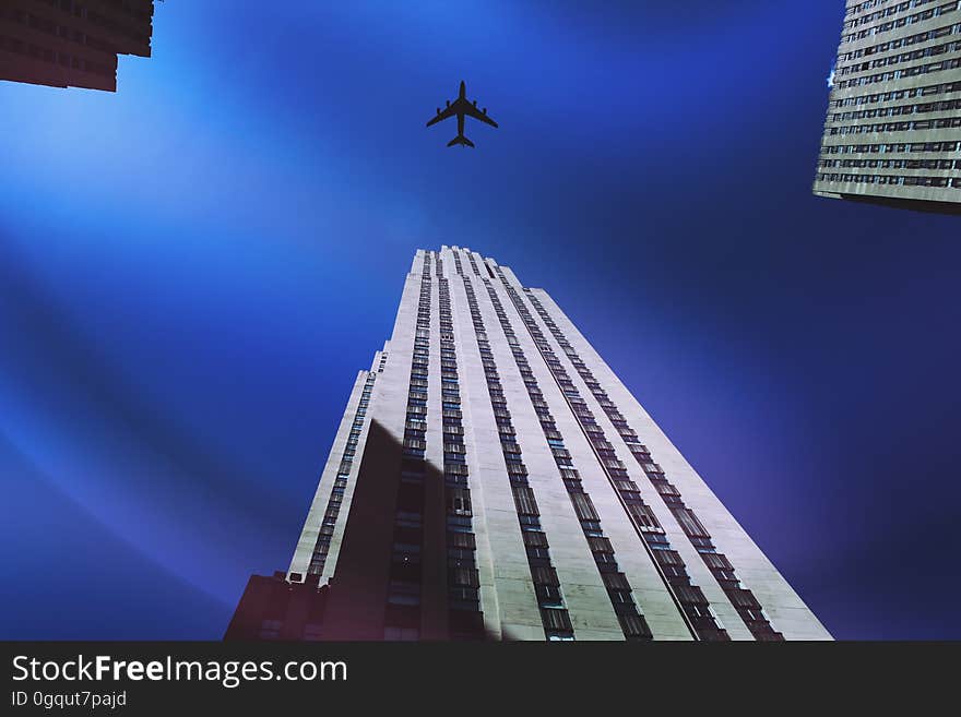 A plane flying over a skyscraper.