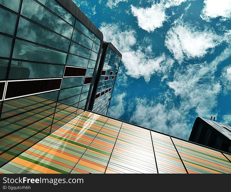 Facade of architecturally designed buildings with one wall in banded pastel colors, reflected in a second glass wall, blue sky and cloud above. Facade of architecturally designed buildings with one wall in banded pastel colors, reflected in a second glass wall, blue sky and cloud above.