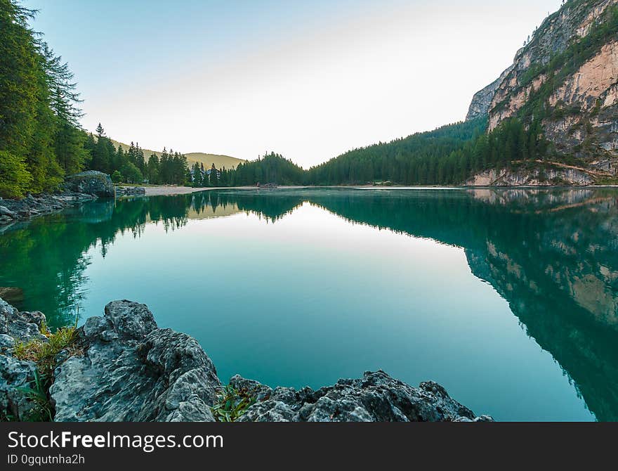 Calm waters reflecting pine trees in alpine lake in Dolomites mountains, Italy on sunny day. Calm waters reflecting pine trees in alpine lake in Dolomites mountains, Italy on sunny day.