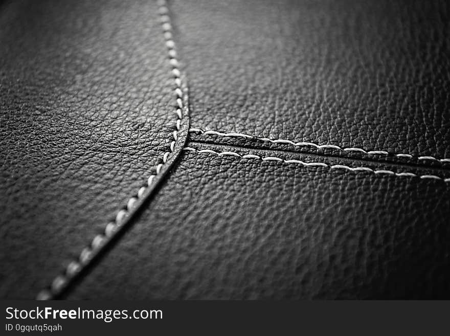 A black and white close up of a leather surface with seams.