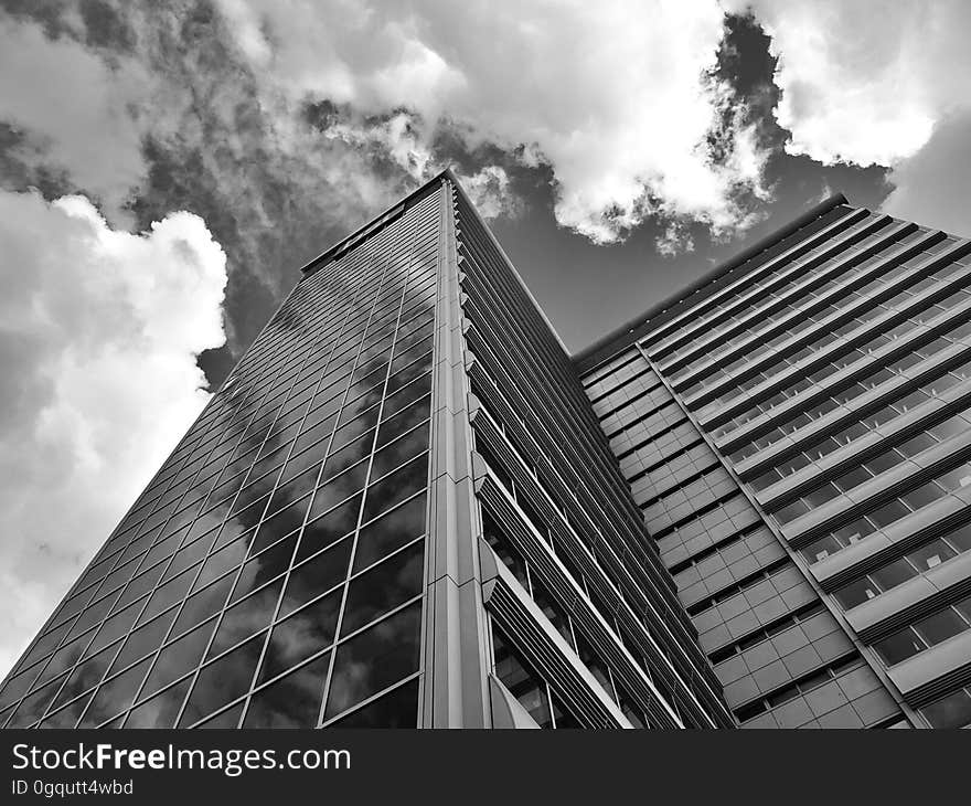 A monochrome photo of a modern high rise building from a low angle.