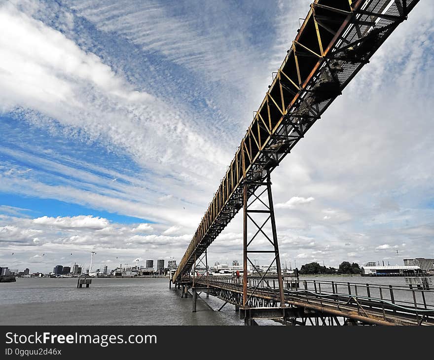 A metal bridge and city skyline in the background.