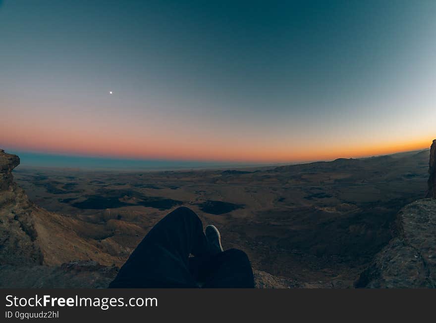 Orange glow of dawn on the horizon of a dark rocky landscape with some blue light in the sky and one star or planet prominent. Orange glow of dawn on the horizon of a dark rocky landscape with some blue light in the sky and one star or planet prominent.