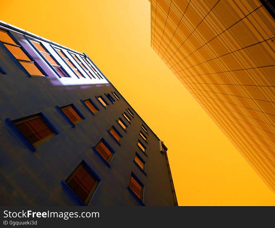 Two neighboring high rise buildings (skyscrapers) with golden sunlight at sunset reflecting off one and lighting parts of the other, also creating an abstract background. Two neighboring high rise buildings (skyscrapers) with golden sunlight at sunset reflecting off one and lighting parts of the other, also creating an abstract background.