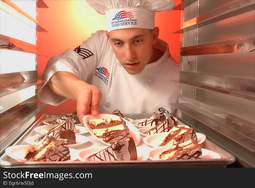 An adult putting cake onto a tray. An adult putting cake onto a tray.