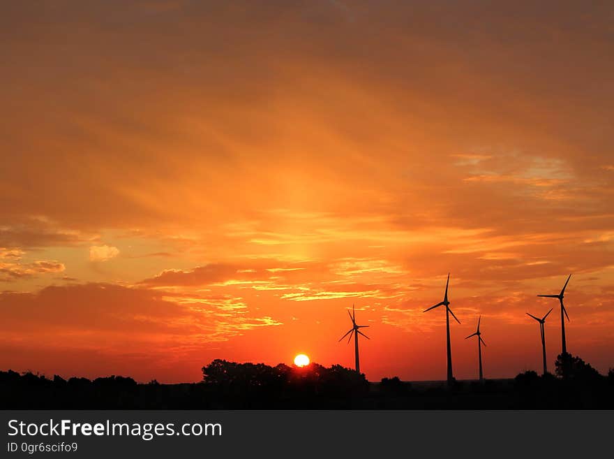 Wind turbines silhouetted in the sunset.