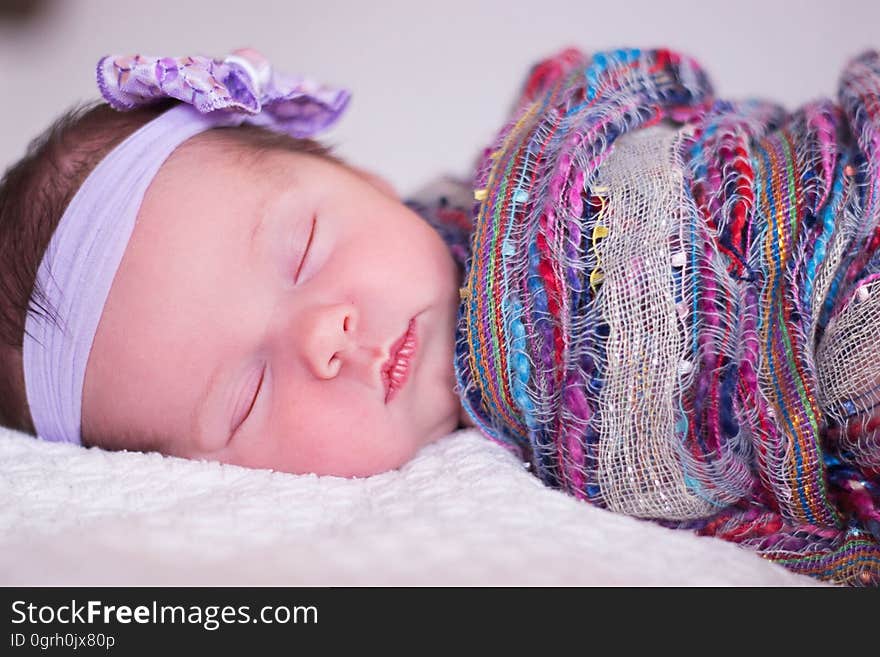 A close up of a baby sleeping under cover. A close up of a baby sleeping under cover.