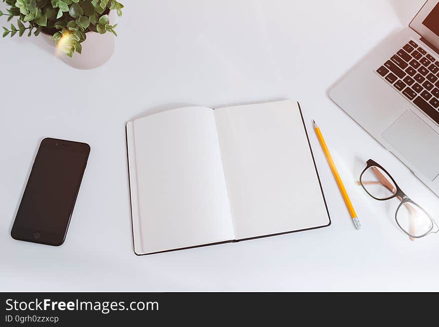 Notebook, pencil, smartphone, laptop, and glasses on a table. Notebook, pencil, smartphone, laptop, and glasses on a table.