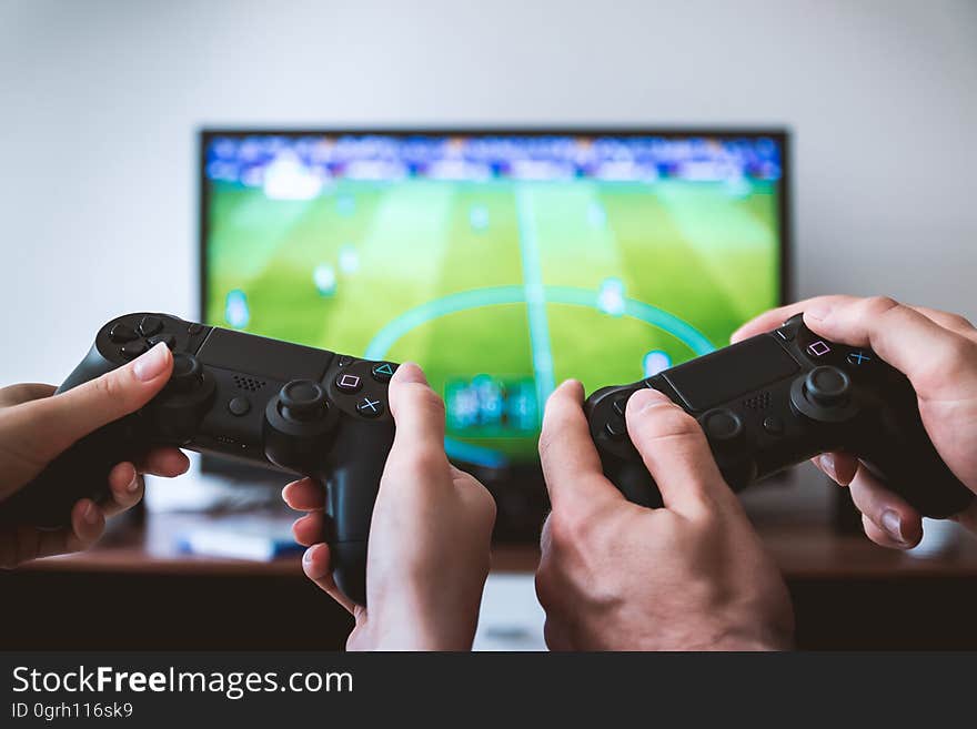 A close up of hands holding gamepads playing a video game.