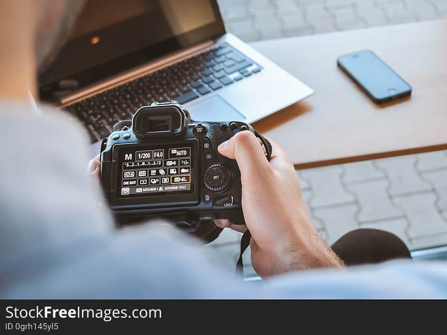 A man checking his camera settings while working outdoors.