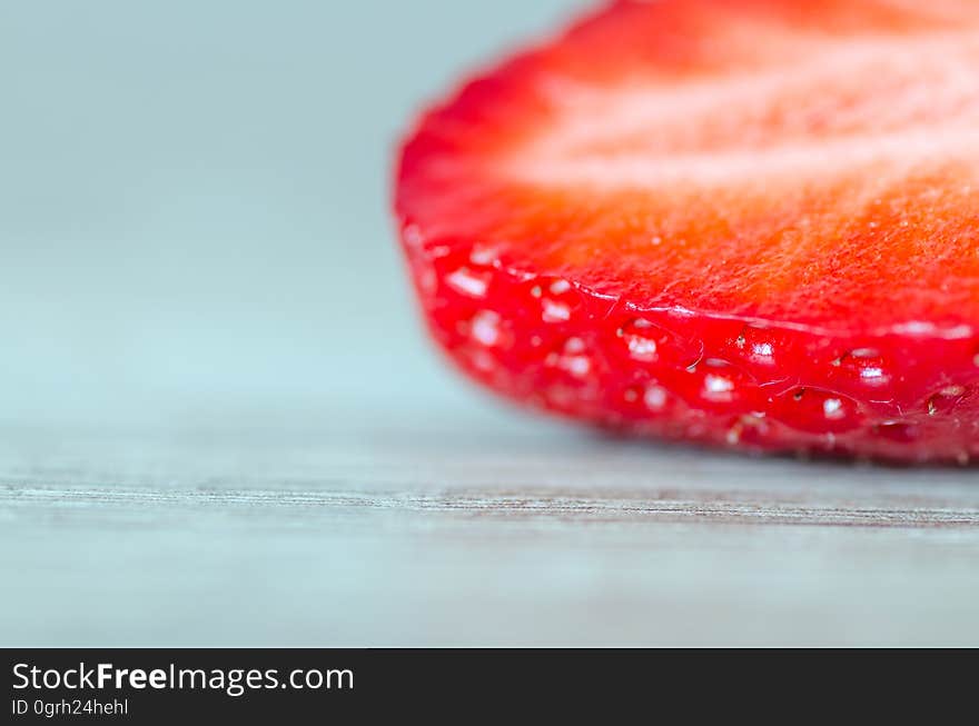 A slice of a strawberry fruit on wood background. A slice of a strawberry fruit on wood background.