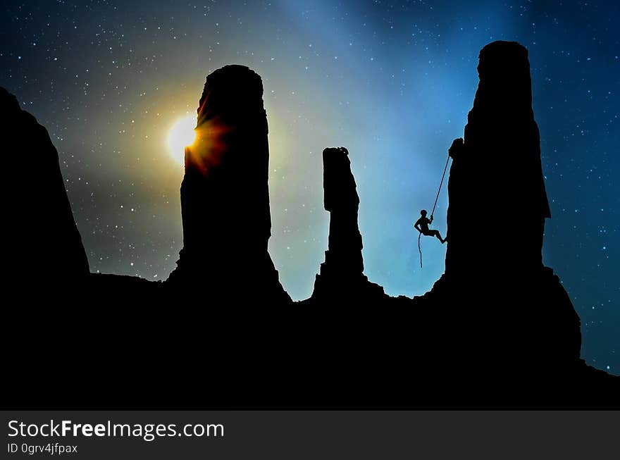 Silhouetted rocks and a cliff climber at dusk. Silhouetted rocks and a cliff climber at dusk.