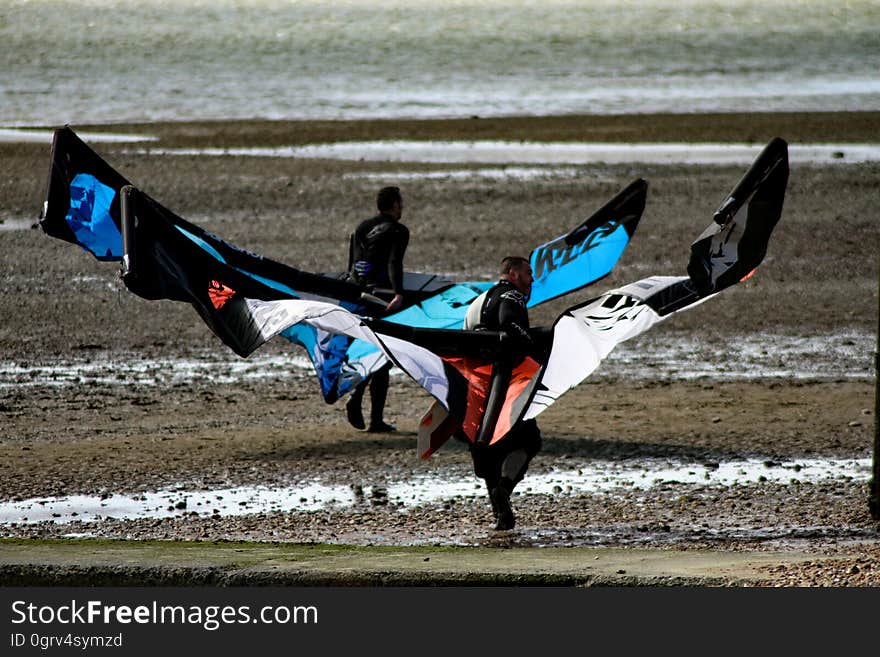 Men Carrying Black Red and White Kite