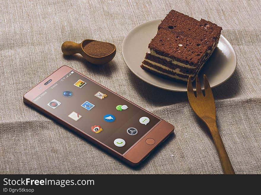 A piece of chocolate cake and a chocolate colored mobile phone. A piece of chocolate cake and a chocolate colored mobile phone.