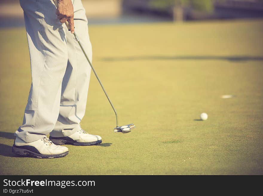 Golf player at the putting green hitting ball into a hole.vintage color