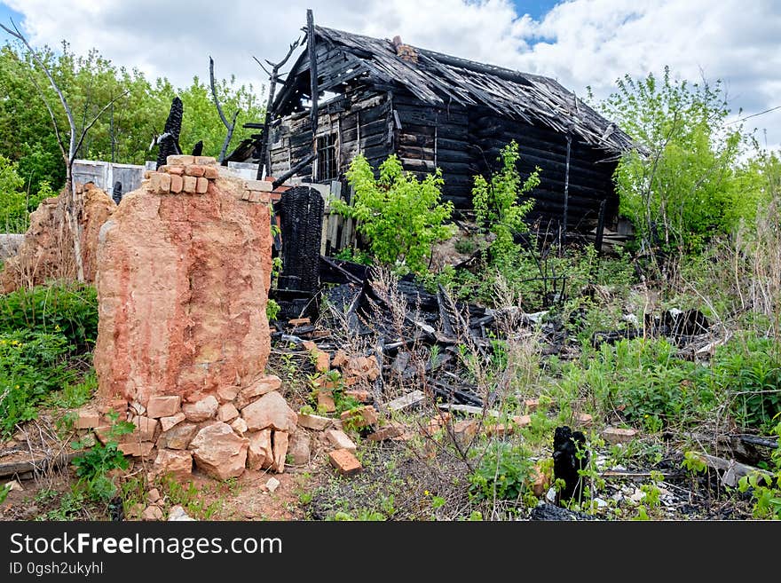 Wooden house after a fire on a background of green trees in the village