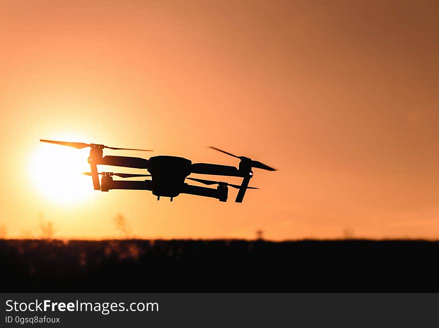 Quadcopter drone flying against setting sun. Quadcopter drone flying against setting sun.