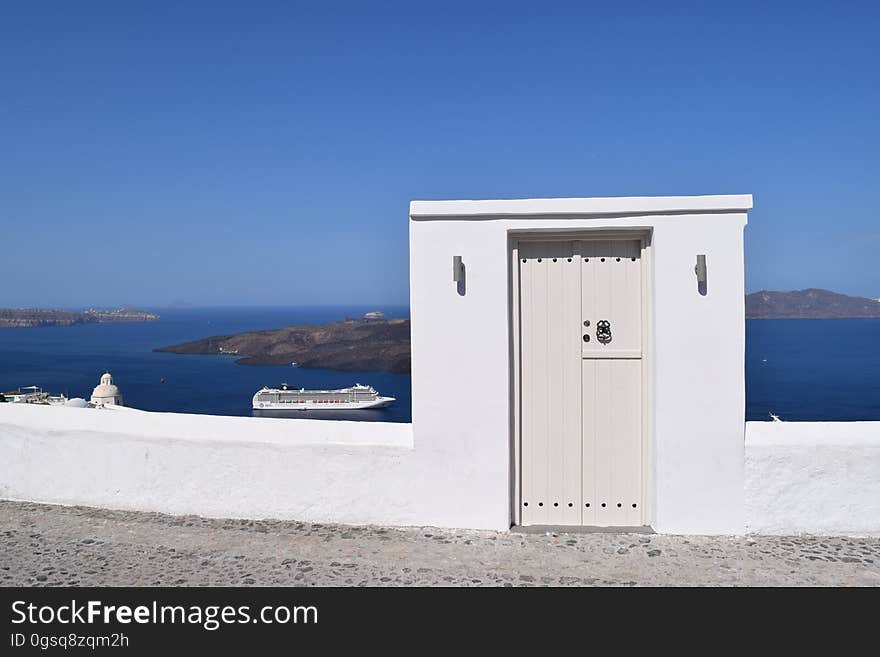 White door on rooftop overlooking cruise ship in blue waters of seaside on sunny day. White door on rooftop overlooking cruise ship in blue waters of seaside on sunny day.