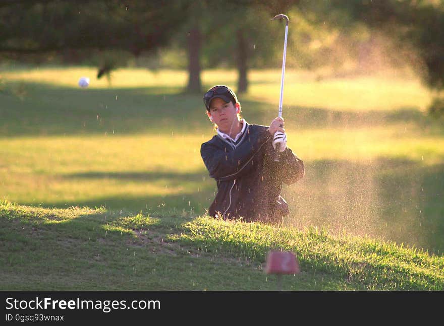 Golfer hitting out of sand trap on sunny course. Golfer hitting out of sand trap on sunny course.