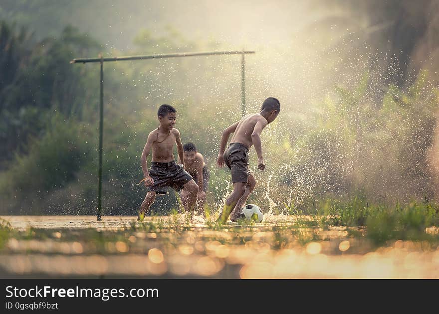 Boys splashing while playing soccer in water on field. Boys splashing while playing soccer in water on field.