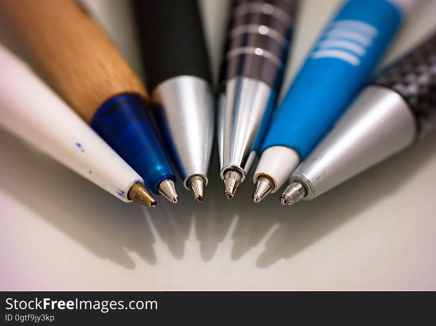 A row of ball point pens on white surface.