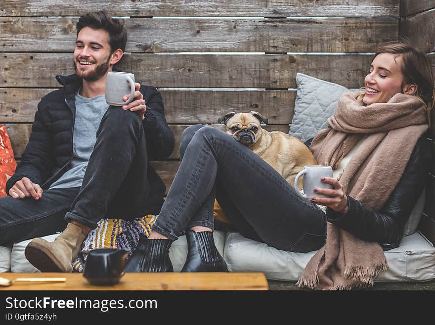 A man and a woman with a pug enjoying some hot drinks in a cafe. A man and a woman with a pug enjoying some hot drinks in a cafe.