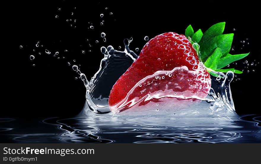 A close up of a strawberry splashing in water.