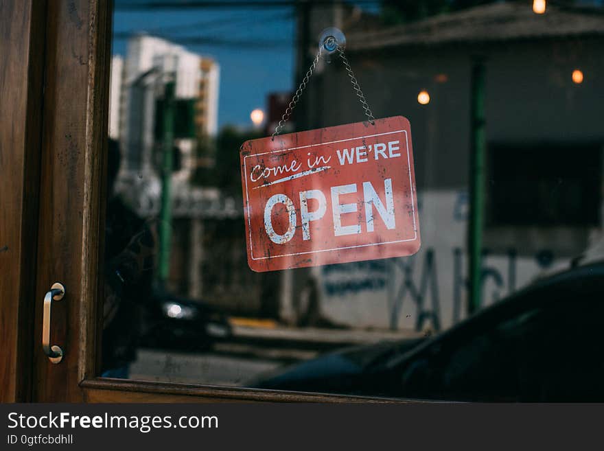 A sign with the text "come in we're open" on the door of an establishment. A sign with the text "come in we're open" on the door of an establishment.