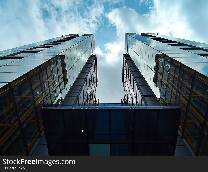 Low angle of steel and glass skyscraper reflecting blue skies and clouds on sunny day. Low angle of steel and glass skyscraper reflecting blue skies and clouds on sunny day.