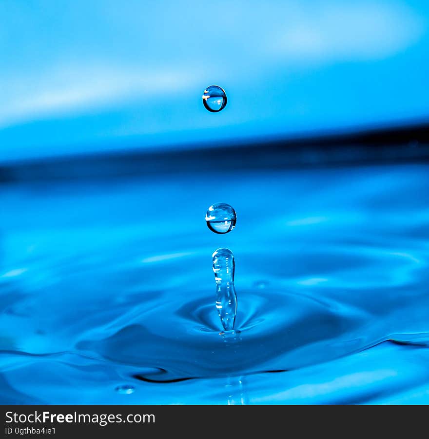 A close up of a drop of water falling in a pool making a splash. A close up of a drop of water falling in a pool making a splash.