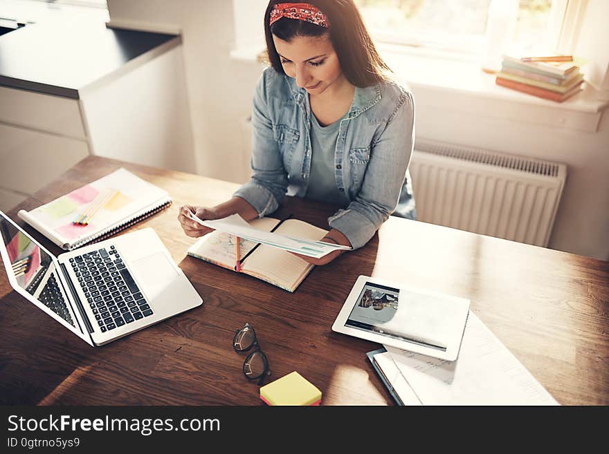 Young female employee working with papers at laptop