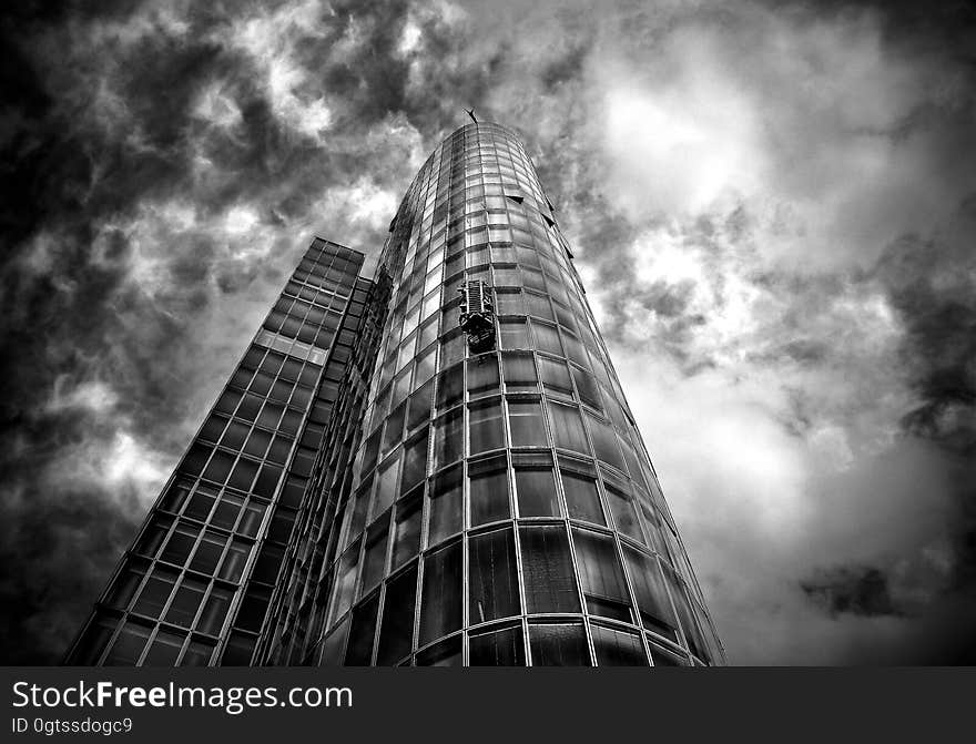 Skyscraper of glass and steel against cloudy skies in black and white. Skyscraper of glass and steel against cloudy skies in black and white.