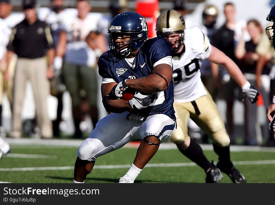 Football players running play on field in daytime. Football players running play on field in daytime.