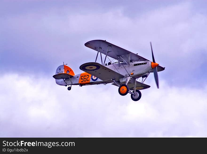 Vintage military prop plane in skies against clouds.