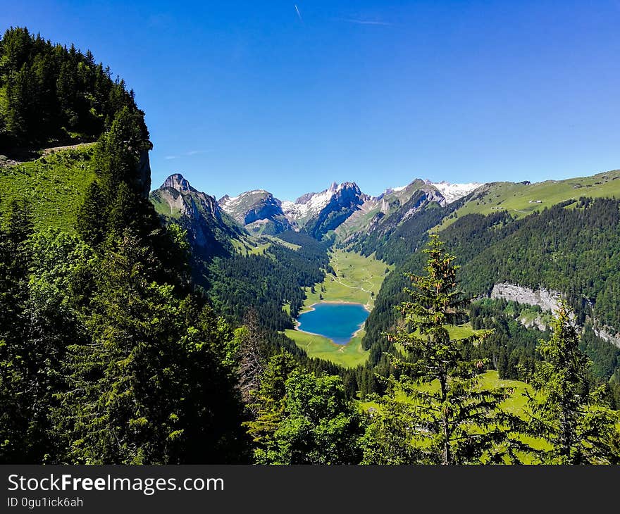 Lake surrounded by forest in alpine valley on sunny day with blue skies. Lake surrounded by forest in alpine valley on sunny day with blue skies.