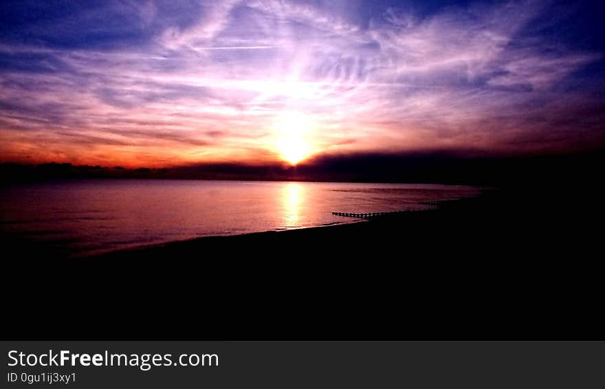 Sunset through clouds over beach. Sunset through clouds over beach.