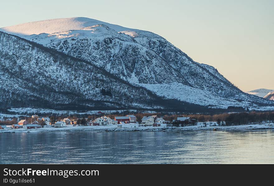 Small village on banks of lake in snow covered mountains in early morning. Small village on banks of lake in snow covered mountains in early morning.