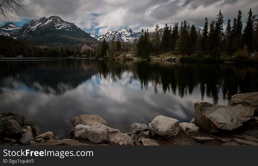 A countryside panorama with a forest, lake and mountain range.