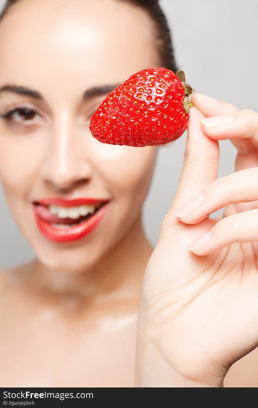 People, emotions, natural, food, beauty and lifestyle concept - Woman Eating Strawberry. Sensual Lips. Manicure and Lipstick. Desire. Beauty Girl Lips with Strawberry. white teeth