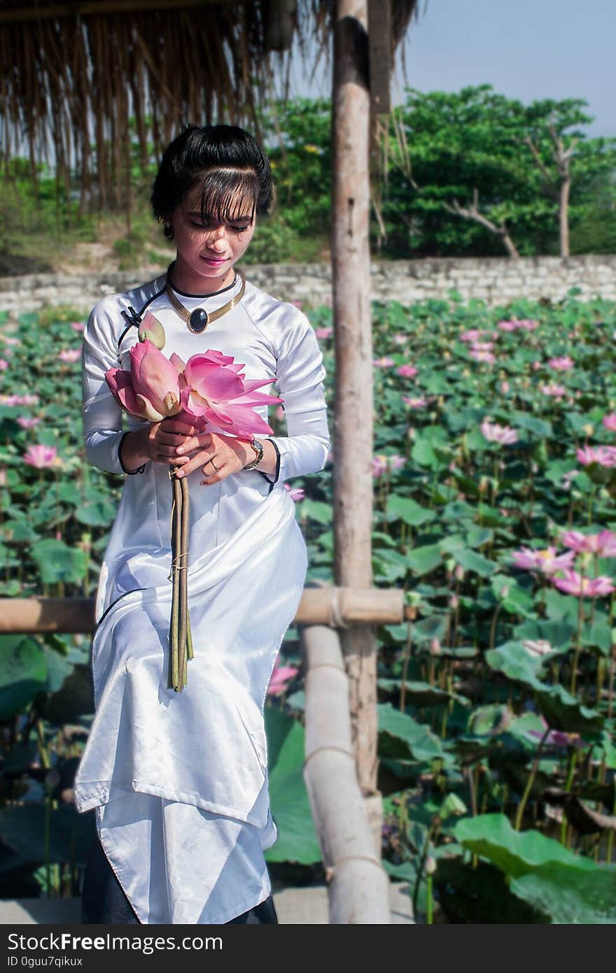 An Asian woman holding lotus flowers.
