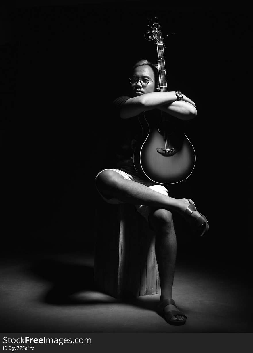 A black and white photo of a man holding a guitar. A black and white photo of a man holding a guitar.