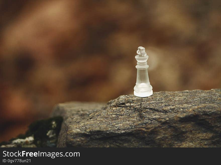 A close up of a glass chess piece on a rock. A close up of a glass chess piece on a rock.