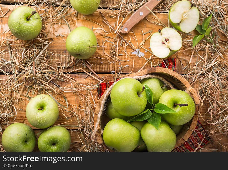 Green apples on wood background with dry grass.