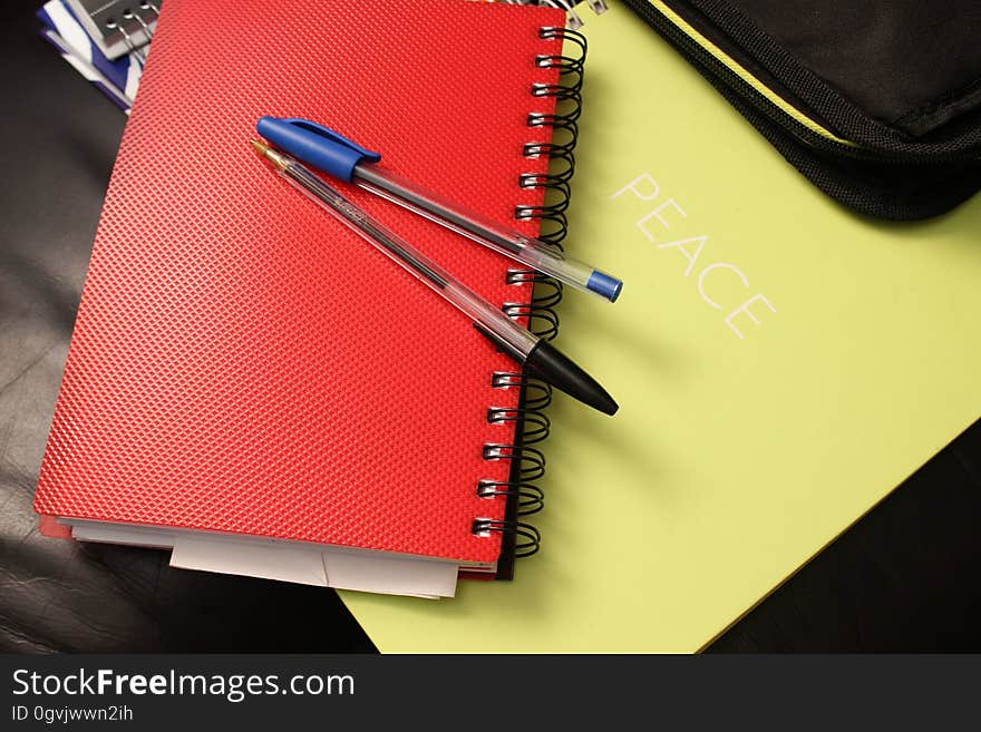 Blue and Black Ball Point Pens on Red Hand Book