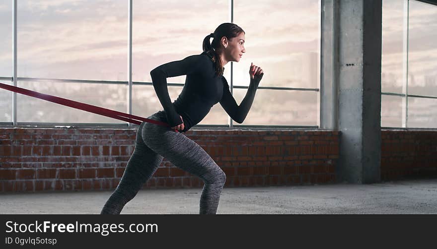 Sports background. Woman athlete doing exercise with sports rubber in the gym