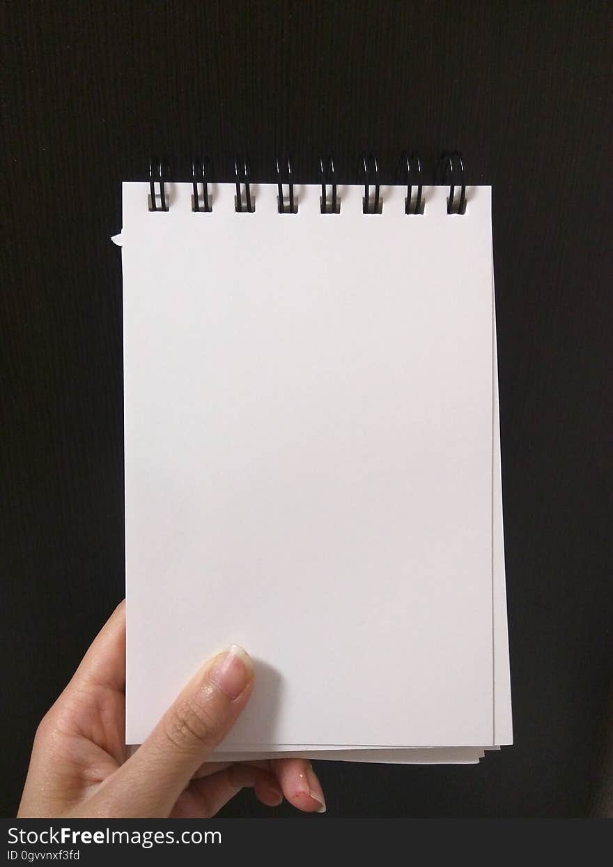 A close up of a hand holding a blank notebook. A close up of a hand holding a blank notebook.